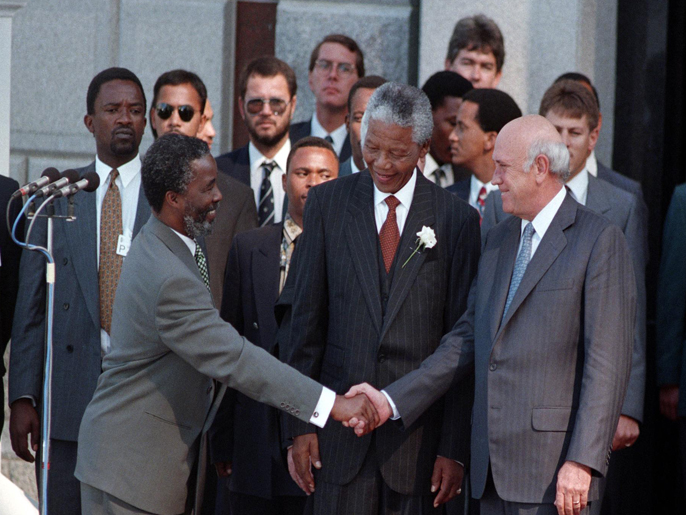 PRETORIA, SOUTH AFRICA - MAY 10: FILE: Nelson Mandela, the newly elected president of the Republic of South Africa, smiles as his Vice-Presidential running mate Thabo Mbeki shakes hands with outgoing president F.W. de Klerk at the start of Mandela