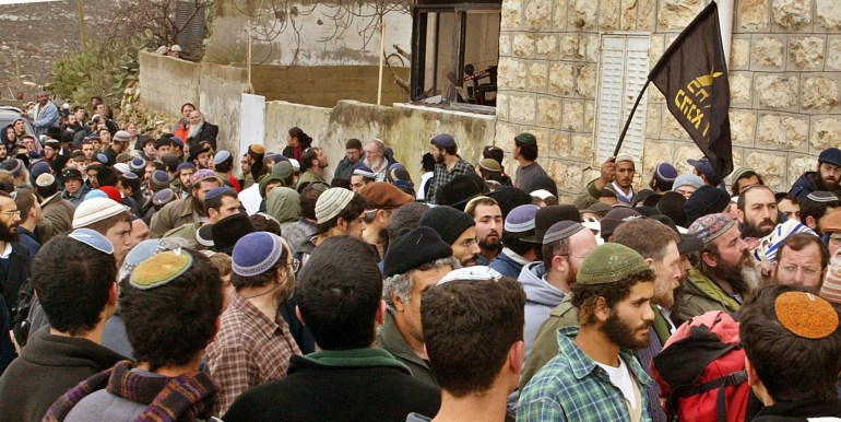 Jewish settlers watch as the body of slain Nathanel Ozeri (R) is